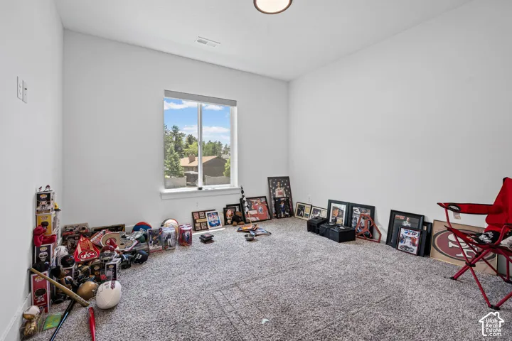 Spacious room with light neutral wall paint, grey patterned carpet, and a large window with white trim
