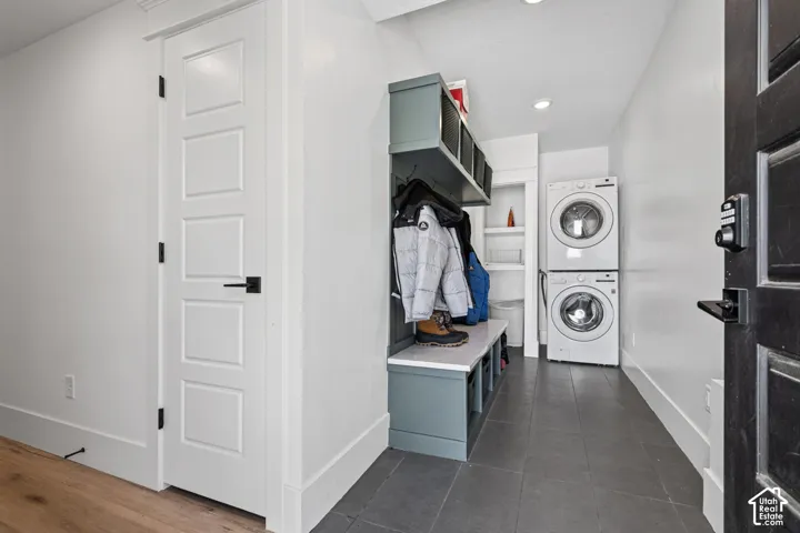 Functional mudroom space featuring a stacked washer and dryer, built-in storage bench, and overhead shelving