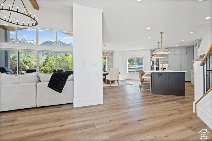 Expansive interior with wood-finish flooring, a kitchen island featuring a light-toned countertop, and a large window arrangement showcasing mountain scenery