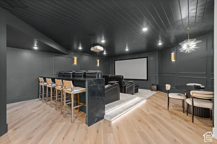 Dedicated home theater featuring a large projection screen, tiered seating, and integrated wall sconces