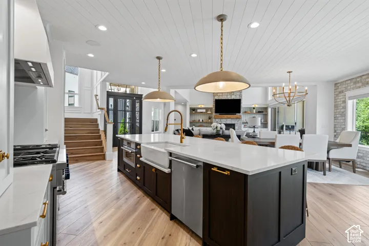 Expansive kitchen island with white countertop and farmhouse sink, featuring pendant lighting and wood-finish flooring