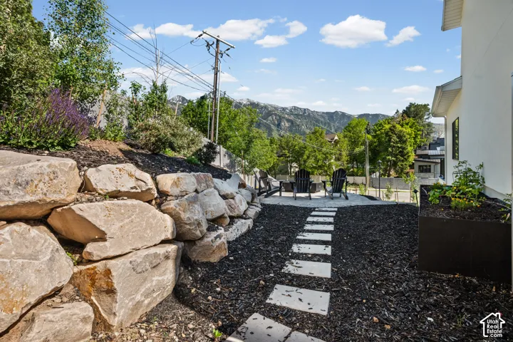 Landscaped exterior featuring a natural stone retaining wall