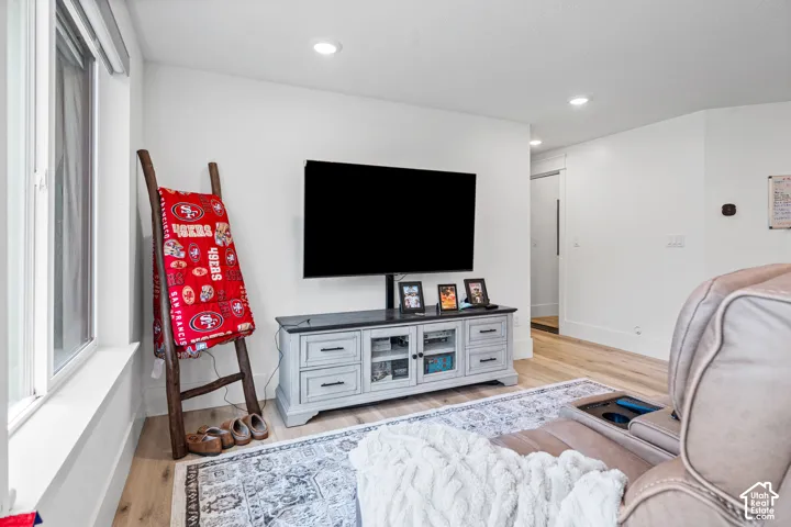 Spacious interior room featuring light wood-finish flooring, white baseboards, and recessed lighting