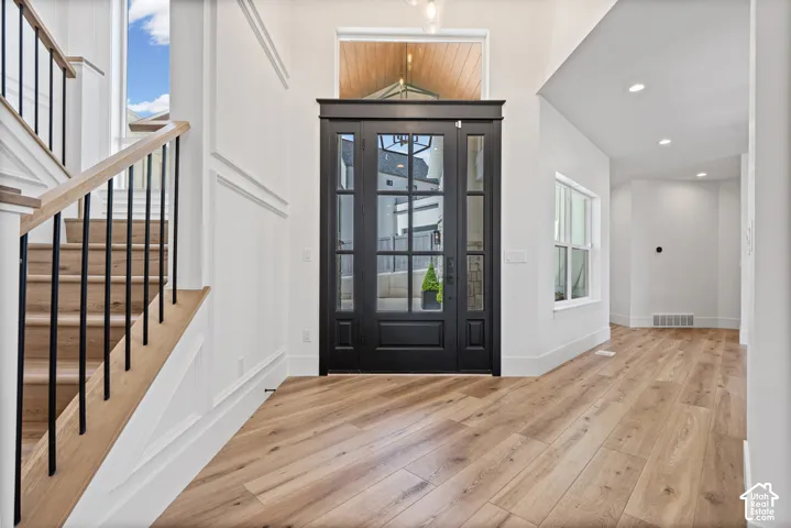 Grand entry featuring double doors with glass panels, a transom window, and wood-finish flooring