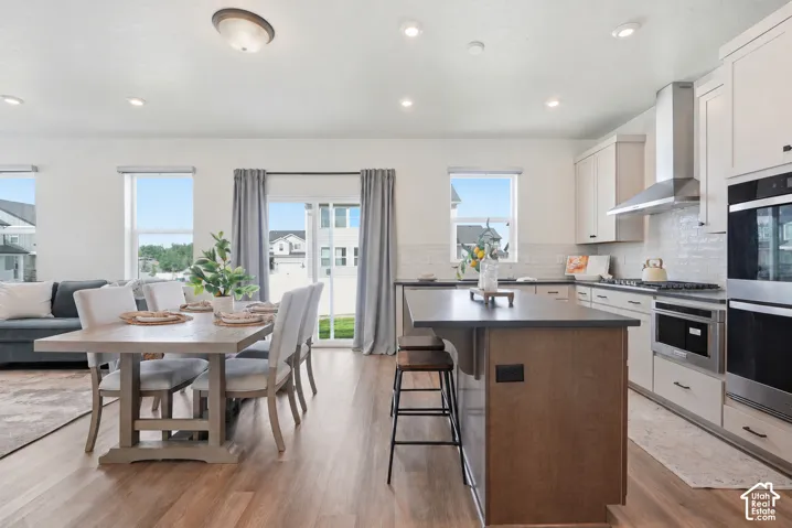 Spacious kitchen featuring stainless steel appliances, a center island with bar seating, and light wood-finish flooring