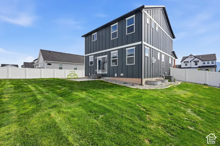 Spacious backyard featuring a manicured lawn, white vinyl fencing, and a concrete patio