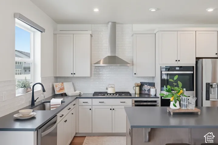 Modern kitchen featuring white shaker cabinetry, stainless steel appliances, dark countertops, a subway tile backsplash, and recessed lighting