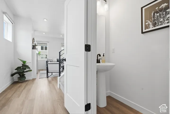 Powder room featuring a pedestal sink with a matte black faucet, mirrored vanity, and modern wall sconce