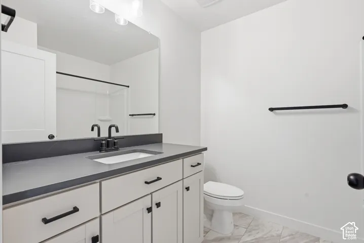 Bathroom featuring a single vanity with shaker-style cabinetry, matte black hardware, a grey countertop, and an integrated sink basin