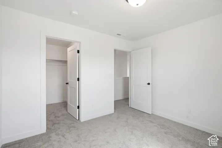 Neutral tone room featuring light gray carpeting, crisp white walls, white baseboards, and a semi-flush ceiling light fixture