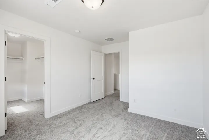 Carpeted room with white walls, two interior doors, and overhead lighting