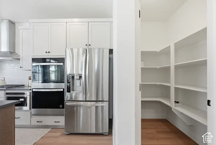 Modern kitchen design featuring white shaker cabinetry, stainless steel appliances, and a built-in wall oven with microwave
