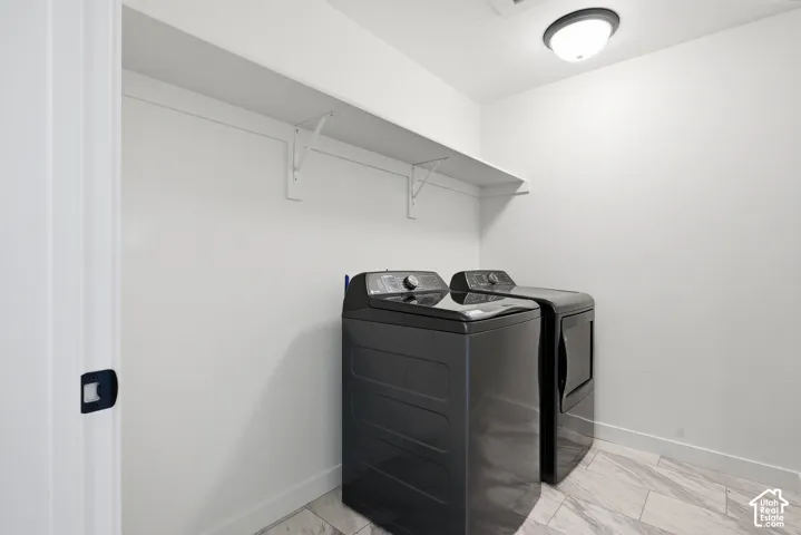 Laundry area featuring a ceiling-mounted light fixture, white walls, built-in shelving, and light-toned tile flooring