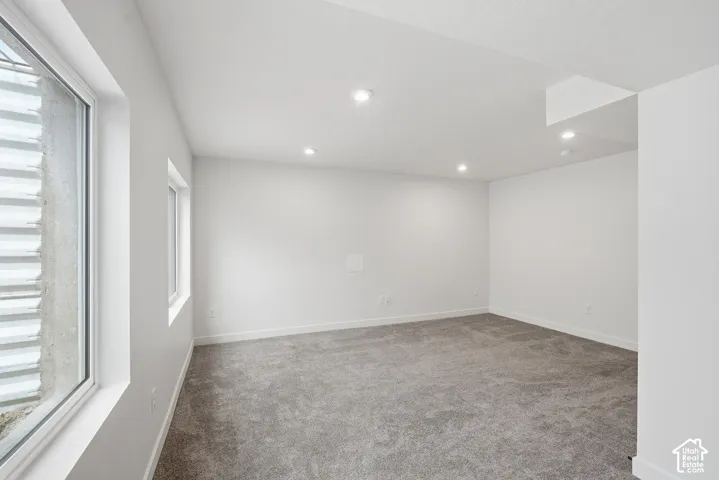 Spacious room featuring light gray carpet, recessed ceiling lighting, and white walls