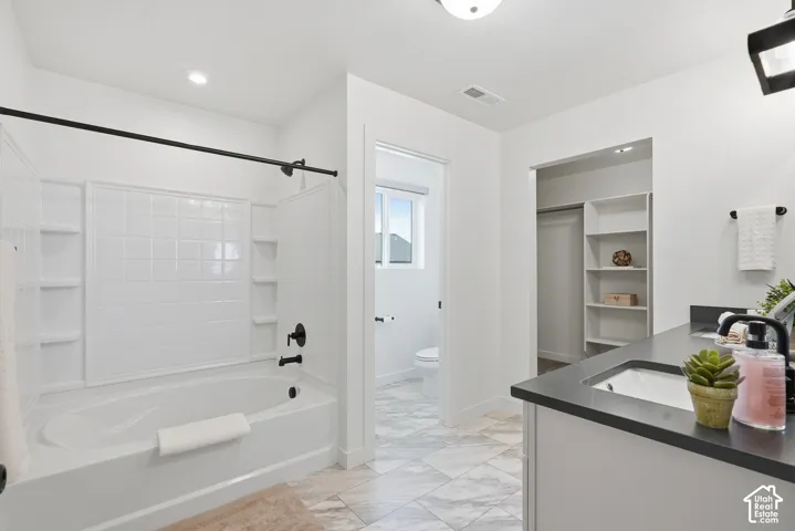 Modern bathroom featuring a white soaking tub with subway tile surround, black plumbing fixtures, and a dual-sink vanity with dark countertop