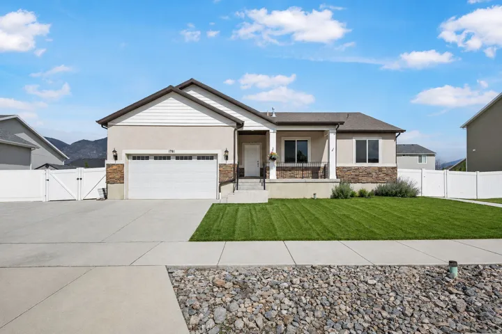 Single-story residence (w/basement) featuring a two-car garage, stone accents, and a covered porch with white columns
