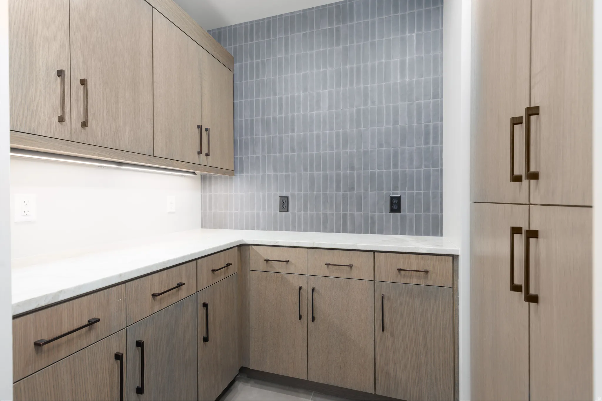 Butler's pantry with custom cabinets, tiled backsplash and under cabinet lighting.