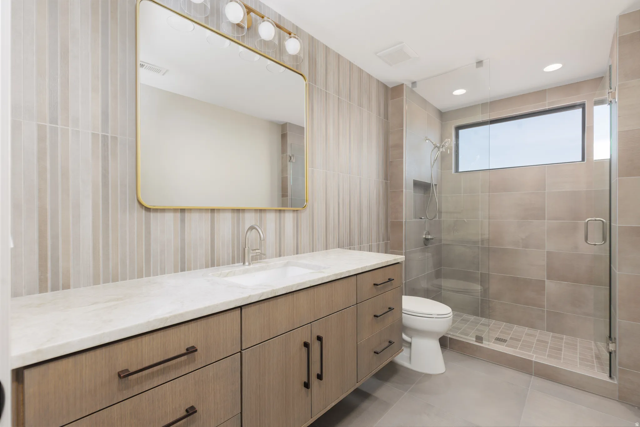 Guest ensuite #2 featuring a full glass shower, tiled backsplash and custom vanity.