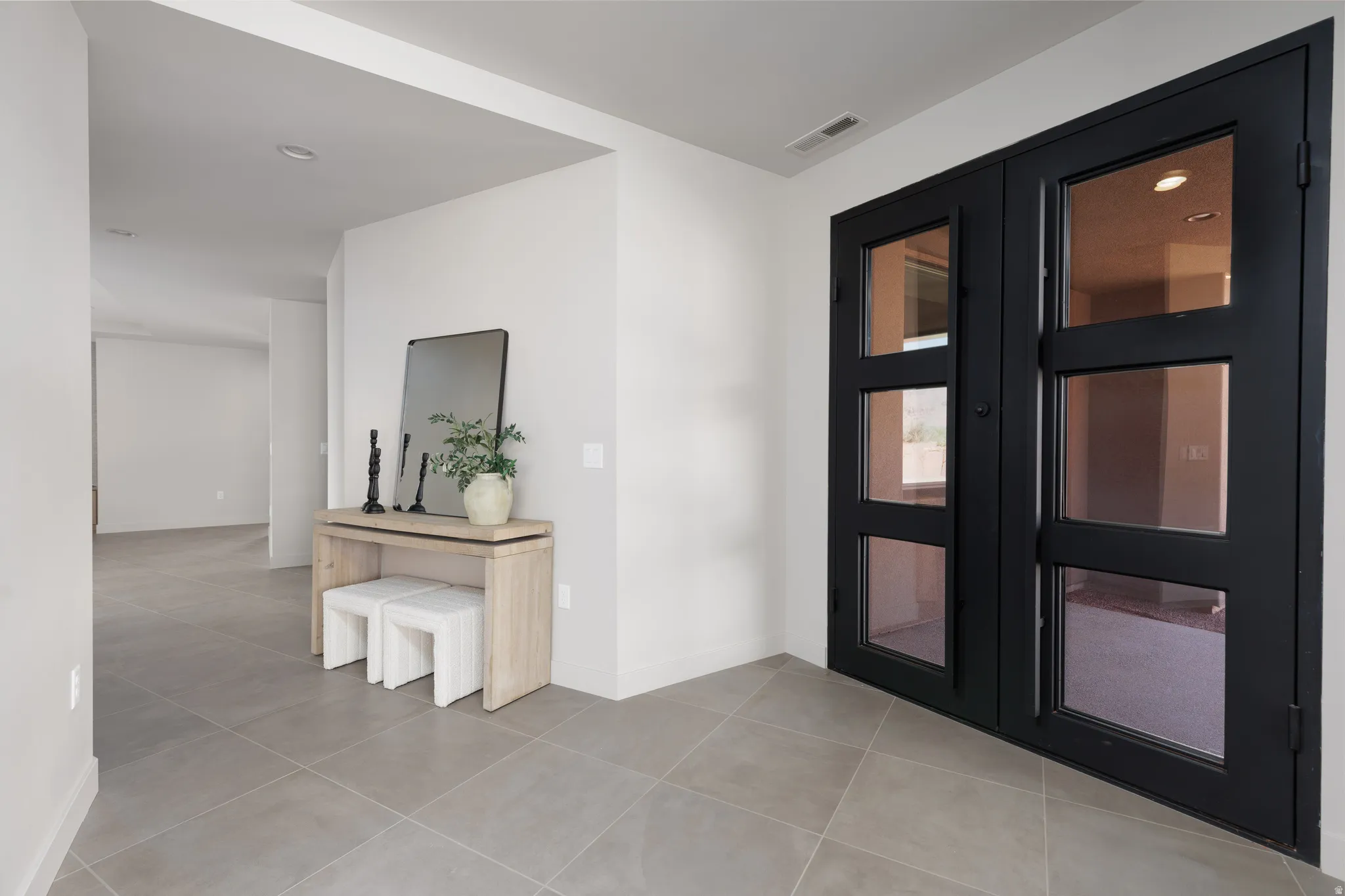Large open entryway featuring a custom built glass iron double door.