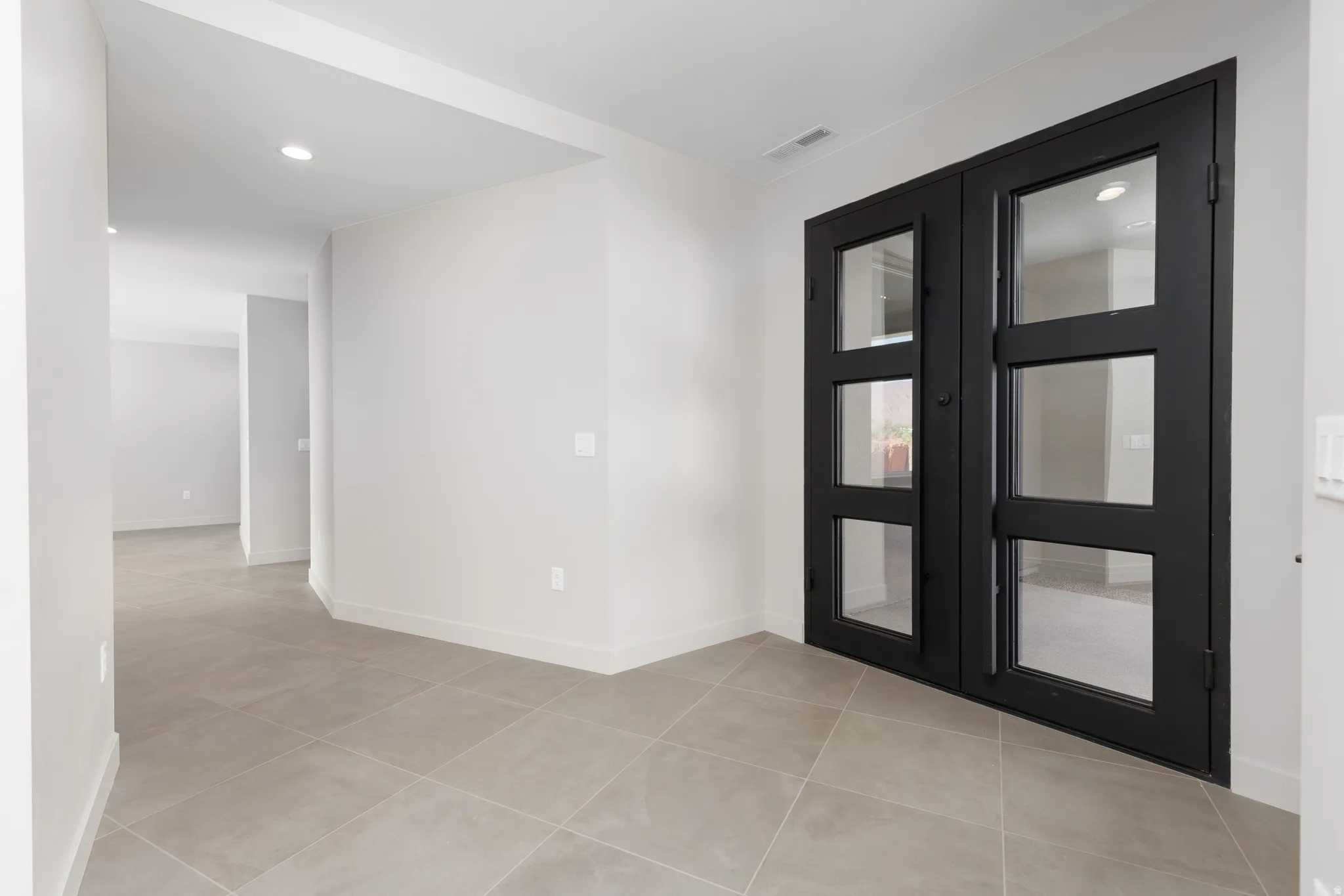 Large open entryway featuring a custom built glass iron double door.