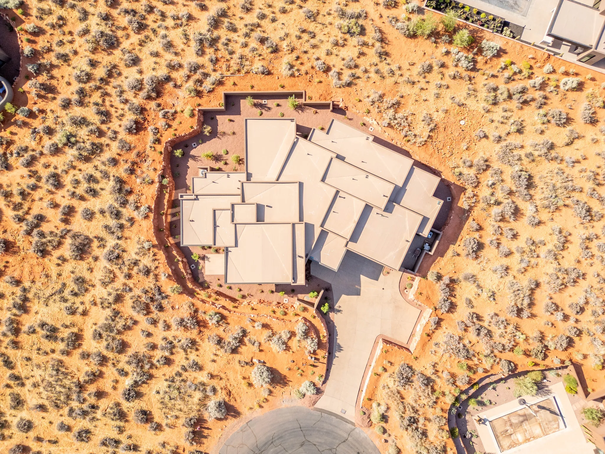 Multi-level roofline, extensive paved driveway, integrated garage, and desert landscaping.