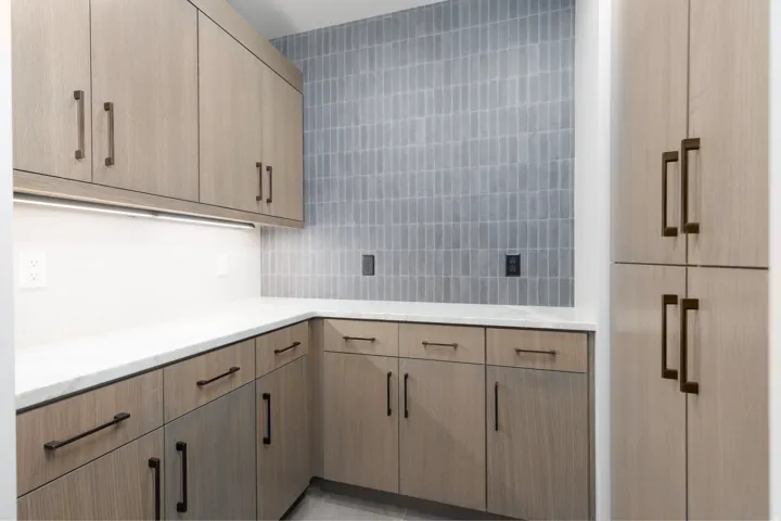 Butler's pantry with custom cabinets, tiled backsplash and under cabinet lighting.