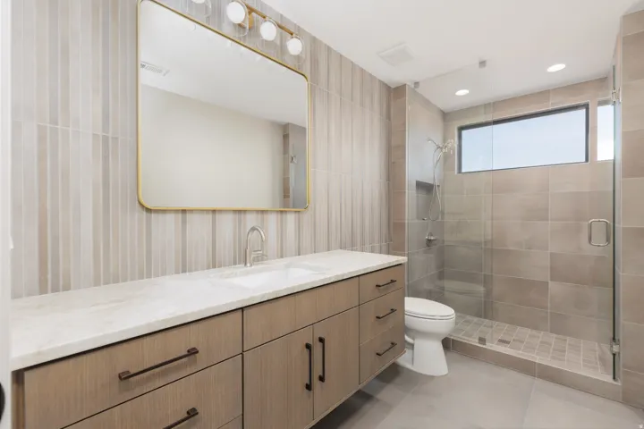 Guest ensuite #2 featuring a full glass shower, tiled backsplash and custom vanity.