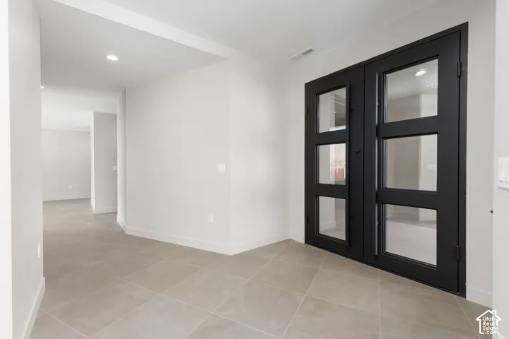Large open entryway featuring a custom built glass iron double door.