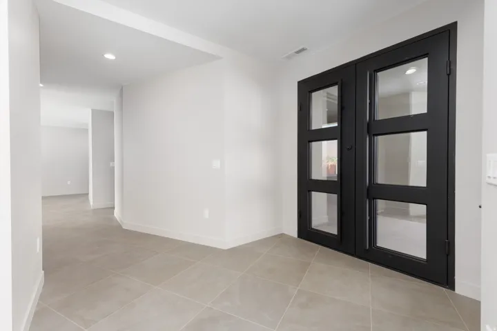Large open entryway featuring a custom built glass iron double door.