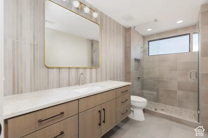 Guest ensuite #2 featuring a full glass shower, tiled backsplash and custom vanity.