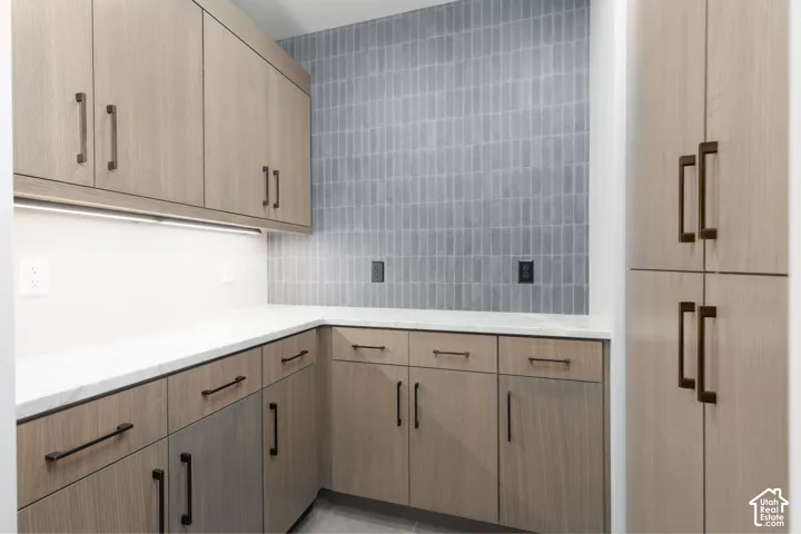 Butler's pantry with custom cabinets, tiled backsplash and under cabinet lighting.