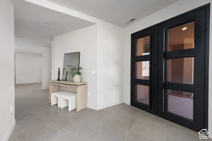 Large open entryway featuring a custom built glass iron double door.