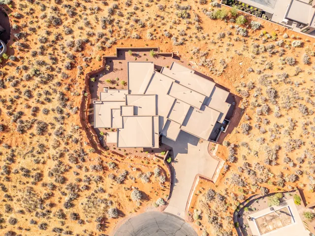 Multi-level roofline, extensive paved driveway, integrated garage, and desert landscaping.