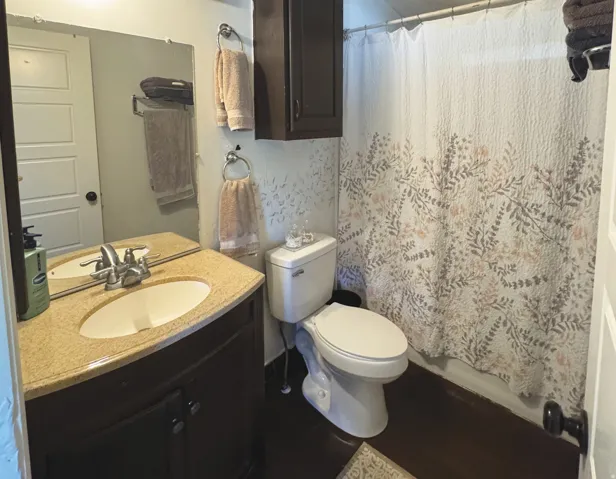 Bathroom featuring a dark wood-finish vanity with a light speckled countertop, an undermount sink, and a chrome faucet