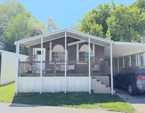 Brown exterior with white trim, featuring a covered front porch with dark wood railings