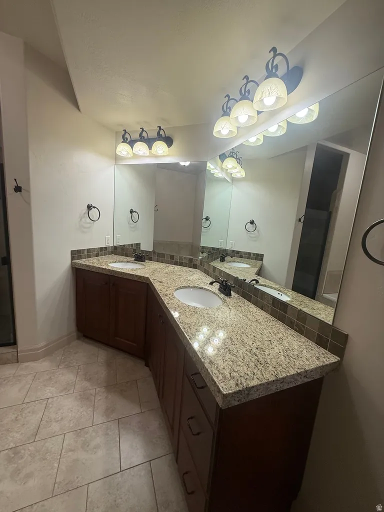 Dual vanity with granite-style countertops, integrated sinks, and dark wood cabinetry