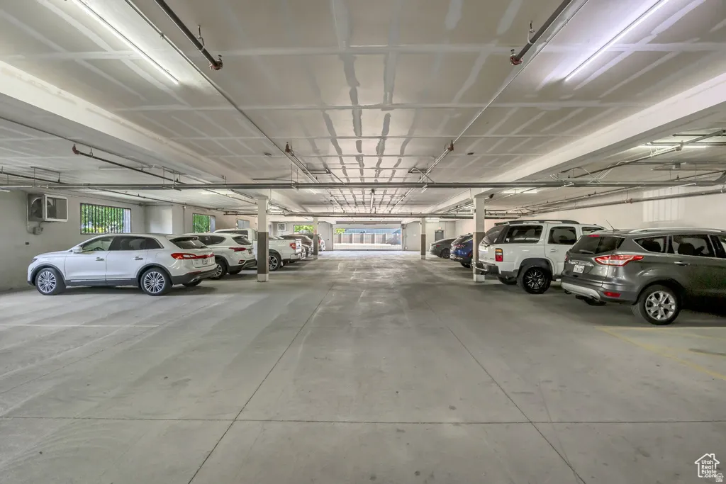 Spacious parking garage featuring concrete flooring, overhead lighting, and painted structural columns