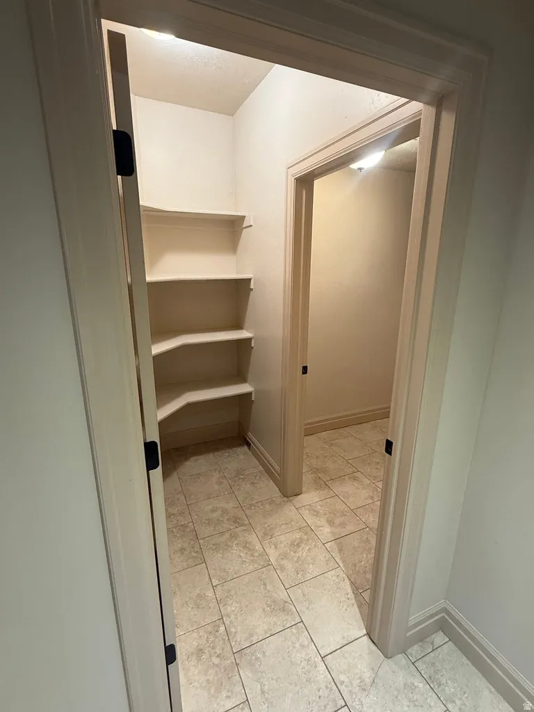 Utility closet with built-in shelving, tiled flooring, and light-toned walls
