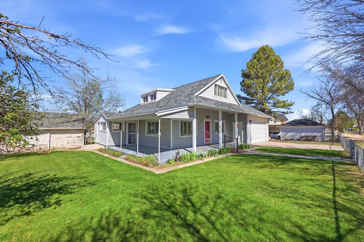 View of front of property featuring covered porch, a garage, a shingled roof, and driveway