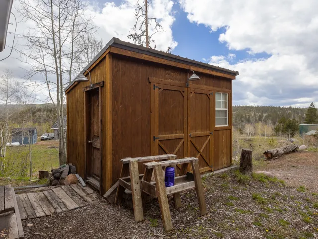 Exterior shed featuring wood-finish siding, a single-pane window, and two barn-style doors