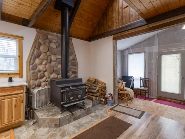 Interior stone-clad fireplace with a wood-burning stove and a slate-look tile hearth