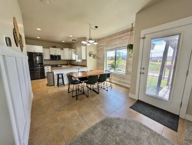 Open-concept kitchen and dining area featuring white cabinetry, a central island with bar seating, and tile flooring