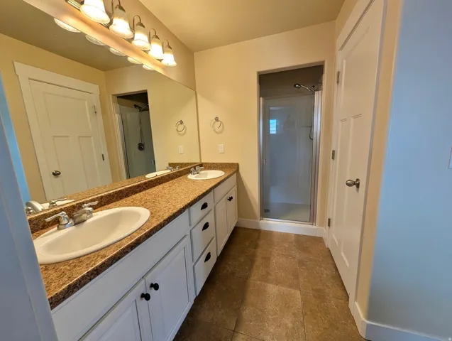 Bathroom featuring a dual vanity with undermount sinks, speckled countertop, and white cabinetry