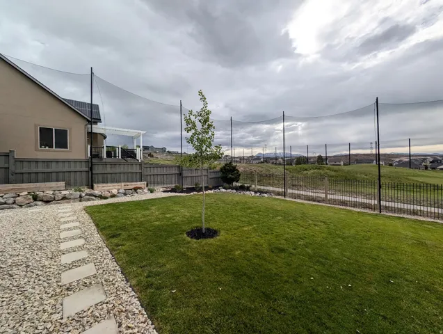 Expansive backyard featuring a lush lawn, gravel path with stepping stones, and a multi-level privacy fence