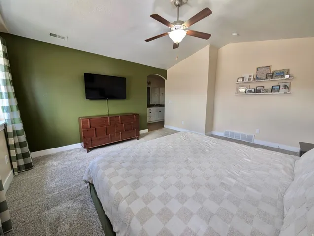 Carpeted room with a ceiling fan, a window with plaid curtains, and a built-in wall niche with shelving