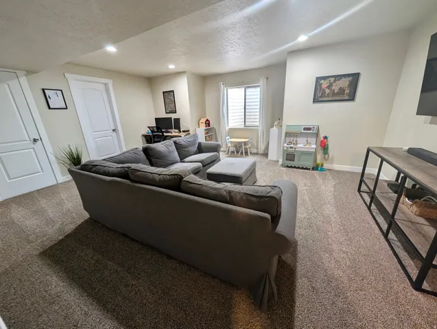 Spacious lower-level area featuring recessed lighting, light-toned carpeting, and a window with horizontal blinds