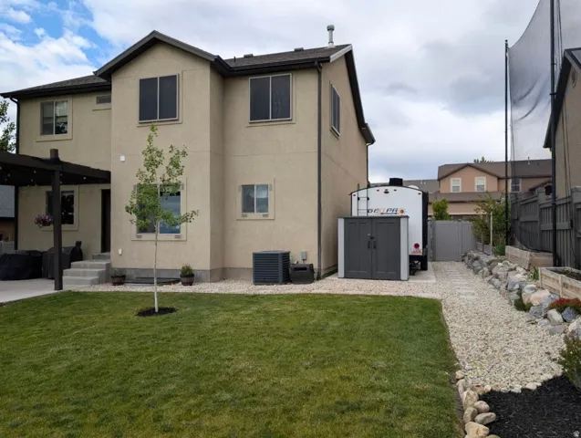 Manicured lawn with a young tree, gravel walkway, and raised garden beds