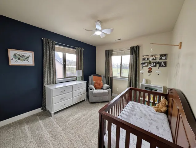 Room with neutral-toned carpeting, dual windows, and ceiling fan