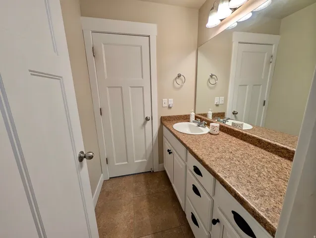 Vanity with an integrated sink, a speckled countertop, and white cabinetry featuring black hardware
