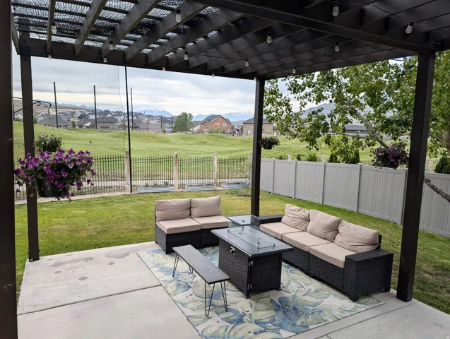 Pergola-covered concrete patio featuring string lighting